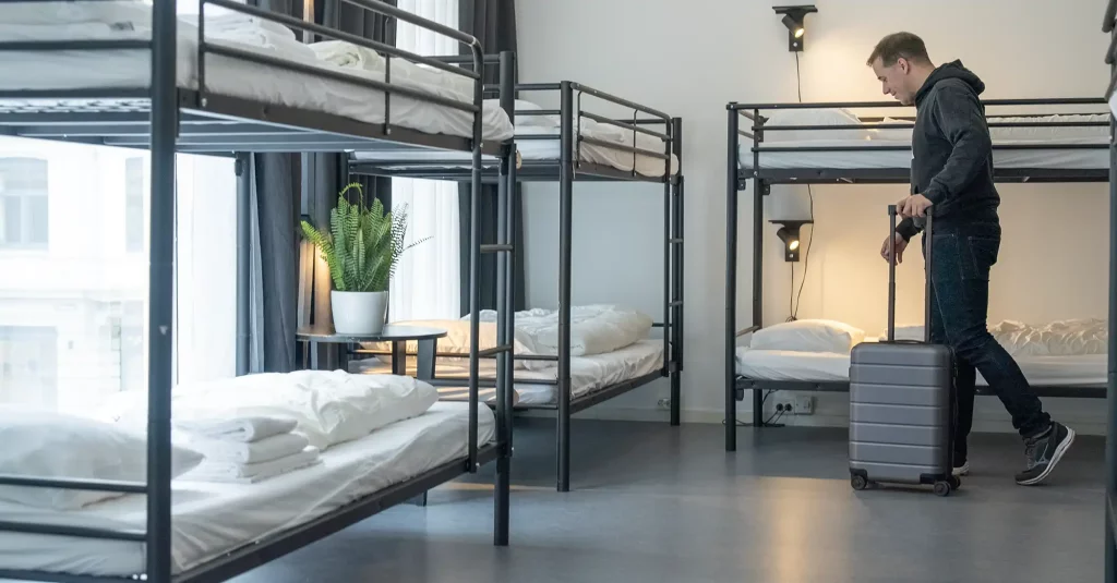 Person, die mit einem Koffer einen Schlafsaal des Hostels betritt.
Foto: Montage