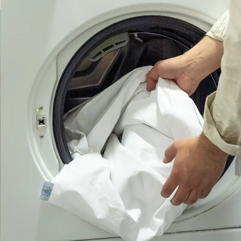 Hands pulling out laundry of the washing machine.